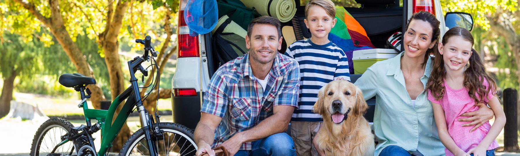 family of four with dog kneeling behind van